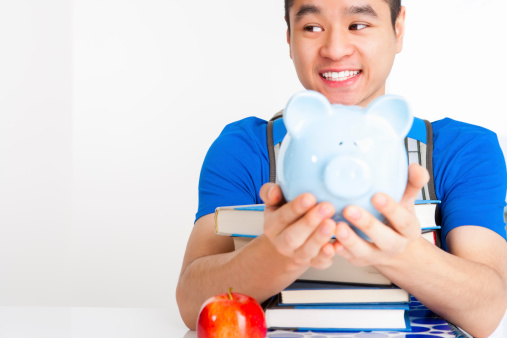 Teenager student holding blue piggy bank