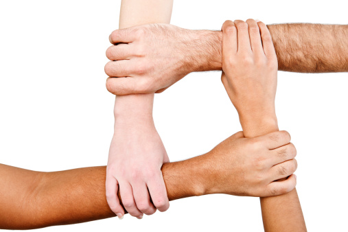 Four multiracial hands are joined together, forming a linked square, isolated against a white background. 