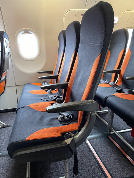 istock Close-up image of airplane cabin interior, foldable table in seat back, rows of empty seats with safety belts lying on cushion, focus on foreground 1685187308