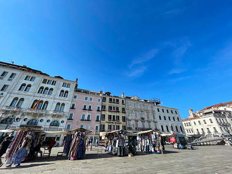 Venice, Italy - July, 14 2023: Stock photo showing close-up view of paved waterfront area lined with waterfront hotels of Venice, Italy with market stalls of outdoor market on Riva degli Schiavoni.