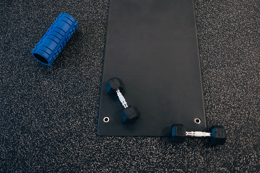 A from above view of dumbells, yoga roller and a mat ready for a daily workout. (copy space)