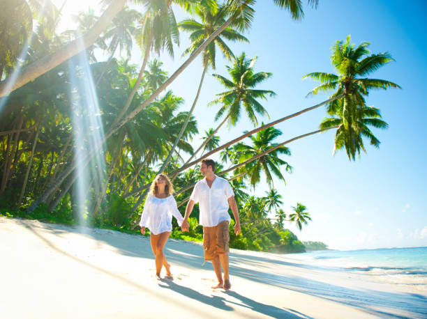 Young Couple relaxing on an idyllic tropical beach Young Couple relaxing on an idyllic tropical beach honeymoon beach stock pictures, royalty-free photos & images