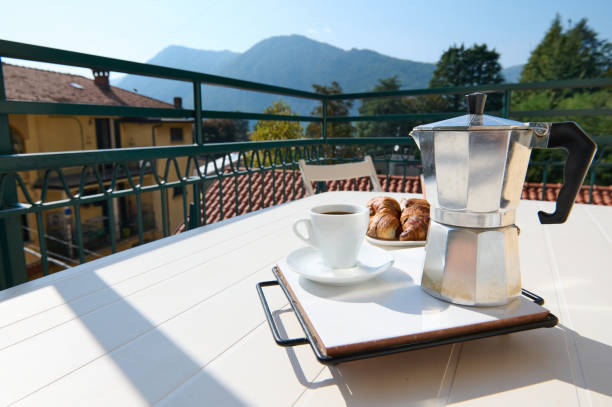 Italian percolator and a cup of freshly brewed coffee on a table on the balcony against the backdrop of the mountains stock photo