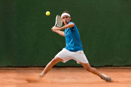 A tennis player during a match. Orange tennis field.