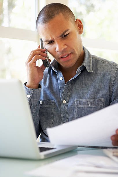 istock Frustrated Young Man On Phone Using Laptop At Home 168533320