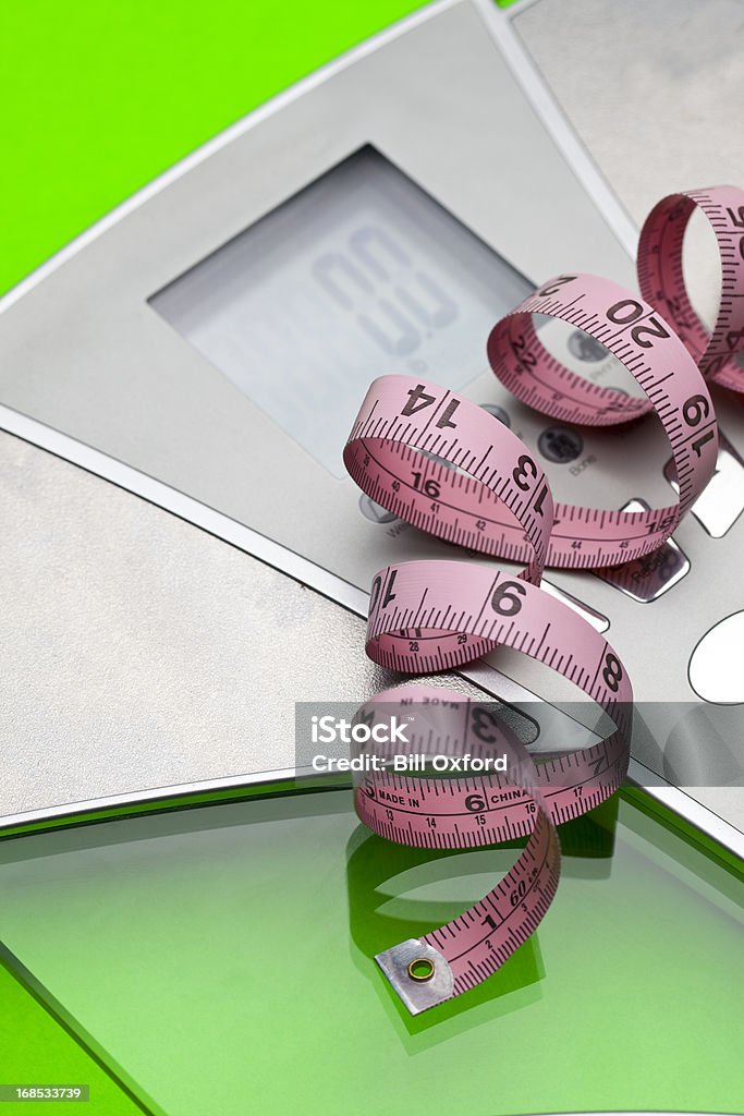 Digital Scale and Tape Digital scale with measuring tape on green background. Mass - Unit of Measurement Stock Photo