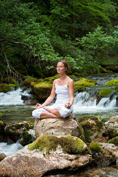 istock Woman meditating in Yoga pose at a mountain stream 168533797