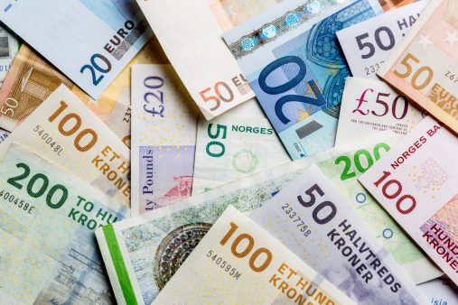 Variety of European Currency including British Pound Sterling, Euro, Danish and Norwegian Kroners well lit and arranged in a pile together.