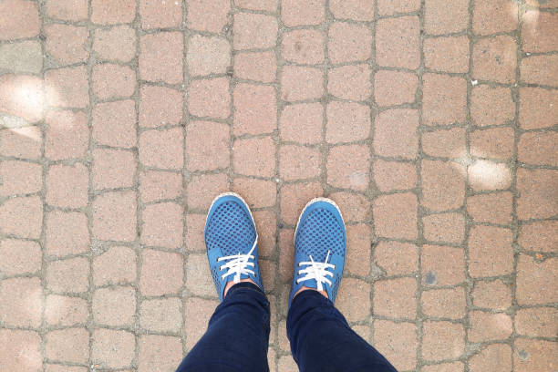 Feet in moccasins stand on sidewalk. View from above.