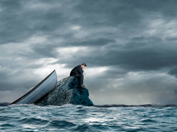 l'uomo e la sua barca si sono arenati su una piccola roccia nell'oceano - storm sea business uncertainty foto e immagini stock