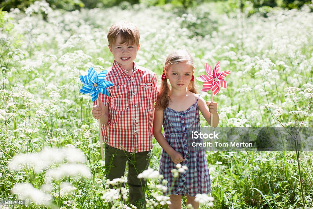 Bambini che giocano con le girandole nel campo di fiori - Foto stock royalty-free di 4-5 anni