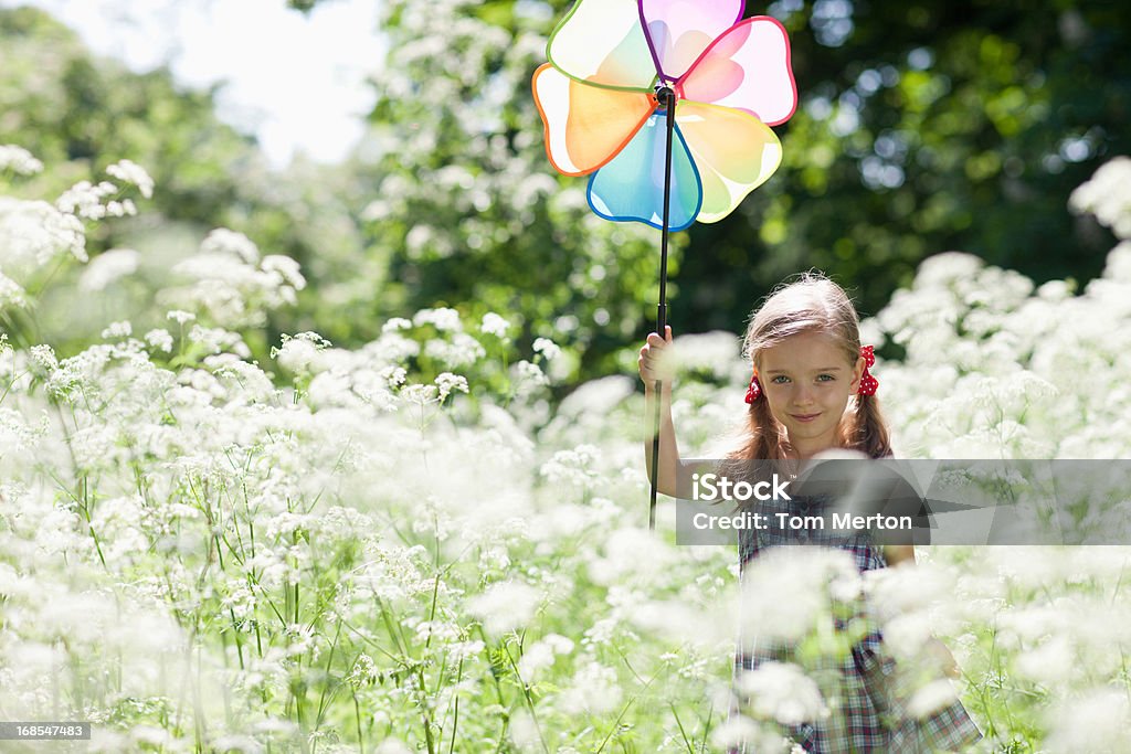 Niña jugando con un MOLINETE en Campo de flores - Foto de stock de 4-5 años libre de derechos