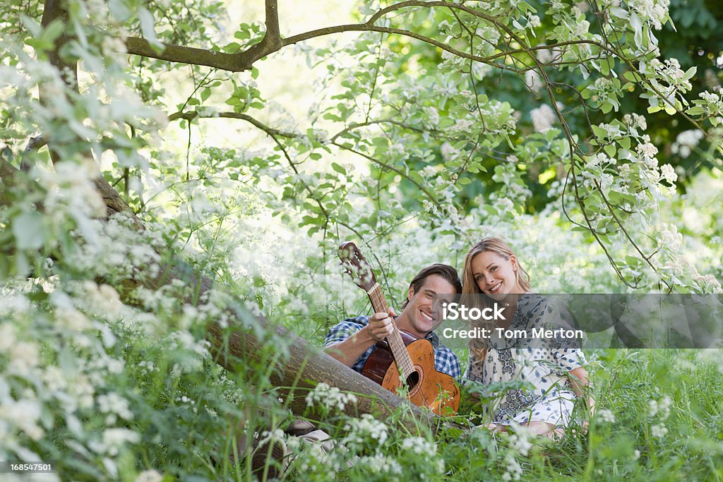 Uomo che Suona la chitarra per ragazza nella foresta - Foto stock royalty-free di 25-29 anni