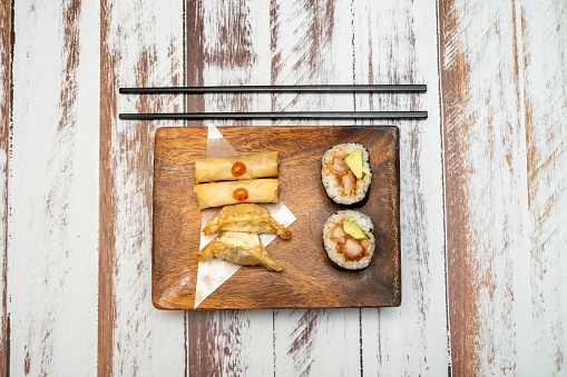 Set of sushi rolls on bamboo serving tray. Uramaki and futomaki roll close-up. Serving Japanese food. Popular Asian dish of rice and seafood on black background.