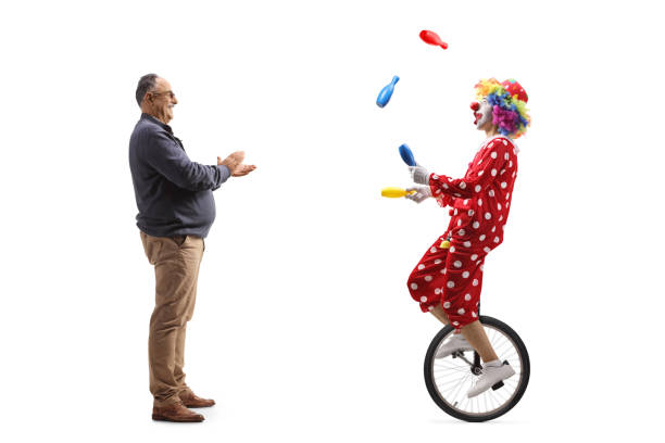 full length profile shot of a mature man giving an applause to a clown riding a unicycle and juggling - unicycle men young adult standing imagens e fotografias de stock