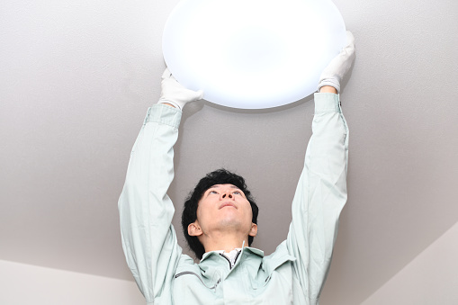Asian male worker inspecting lighting equipment