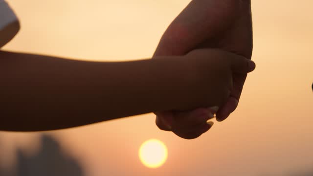Close up of mother and a child hands at the sunset