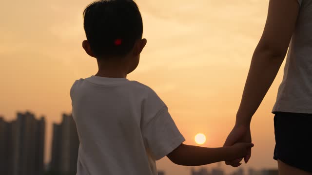 Close up of mother and a child hands at the sunset