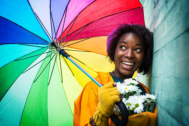 felice giorno di pioggia in città - candid women african descent umbrella foto e immagini stock