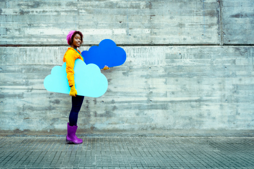 Young casual woman carrying blue clouds: cloud computing concept.