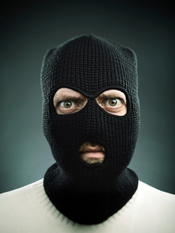 Man with a balaclava looking at camera. Black background.