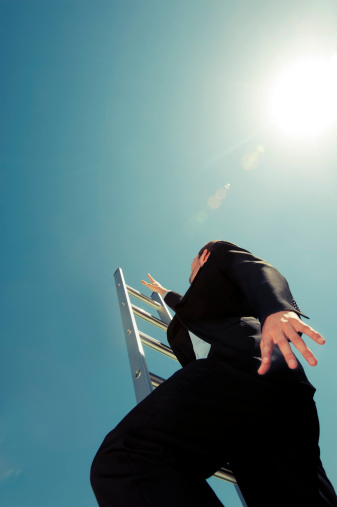 Businessman climbing the Ladder of success with blue sky background and copy space. Cross processed