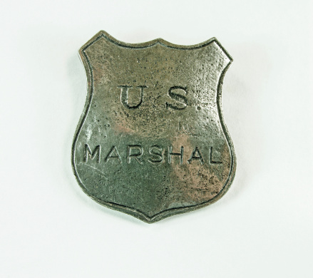 An old worn  US marshal badge on white... Close-up.