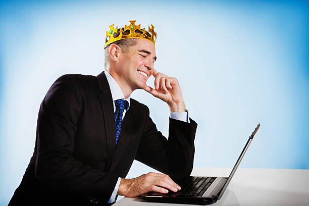 istock Crowned businessman smiles down at his laptop 168584037