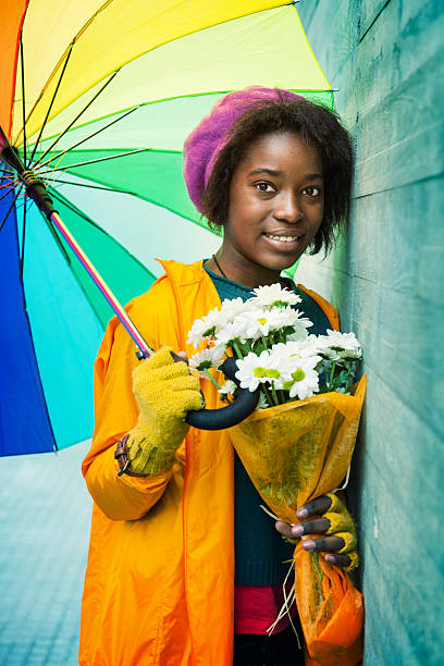 giovane donna in un giorno di pioggia - candid women african descent umbrella foto e immagini stock