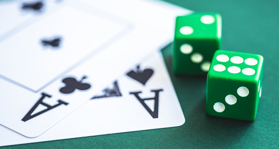 Green dice and playing cards on poker table