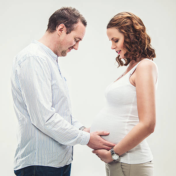 embarazo mujer y hombre mirando su creciente de vientre - human pregnancy flash fotografías e imágenes de stock