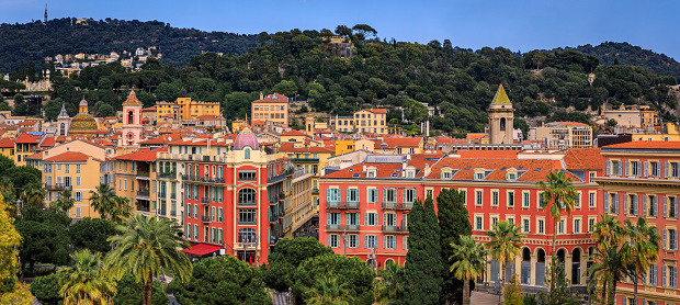 Aerial view of Old Town or Vielle Ville buildings, the trees of Promenade du Paillon and Castle Hill or Colline du Chateau at sunset in Nice, France