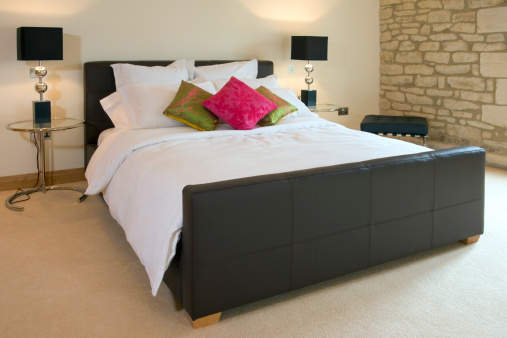 Contemporary leather covered double bed with bedside tables and lamps