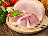 Cooked Ham Slices on a wooden Plate