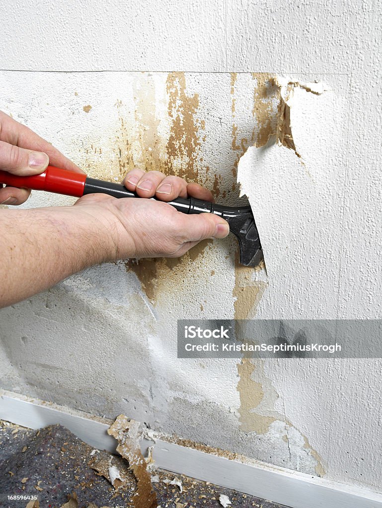 Fixing damage in wall.... Man taking of old wall paper to fix a humidity damage.... Adult Stock Photo