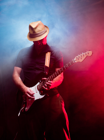 A Blues guitarist jamming on stage with stage lighting.