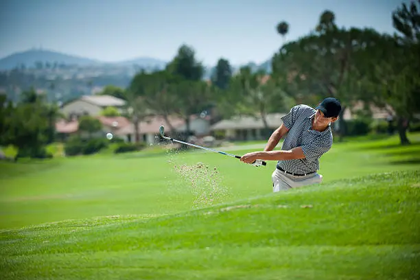 An image of a golfer hitting out of a sand trap.