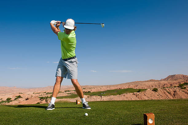 Tee Shot A golfer at the top of his swing teeing off in the desert. golfer swinging club stock pictures, royalty-free photos & images