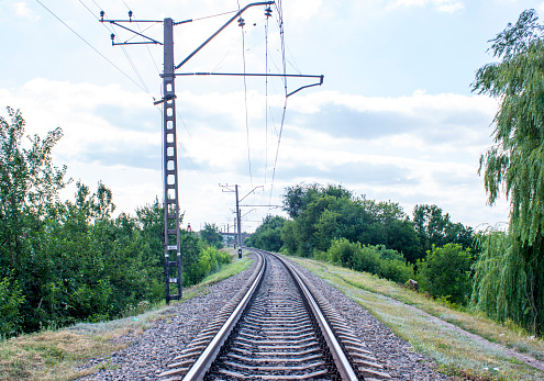 Photo of a railroad track, a railroad track in the grass. Power line poles and railroad tracks.