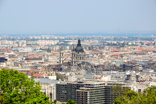 View on Budapest from Gellert Hill, Hungary. Houses, the Basilica of St. Stephen in the background of the foggy morning sky. City panorama. Selective focus.
