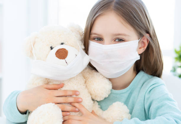 istock Girl with plush teddy wearing masks 1686058247