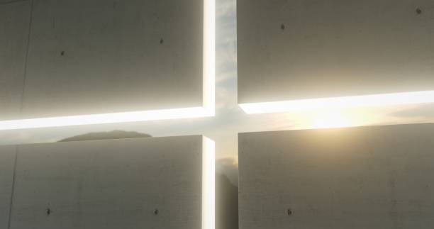 The sun casts its rays through the cross-shaped aperture in the wall of a contemporary church, filling the space with a warm and serene light.