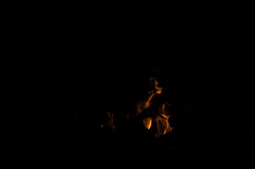 Captivating bonfire on black background: bright flame, cozy darkness, no people.