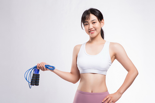 Woman Preparing for Jump Rope Training in front of Gray Background