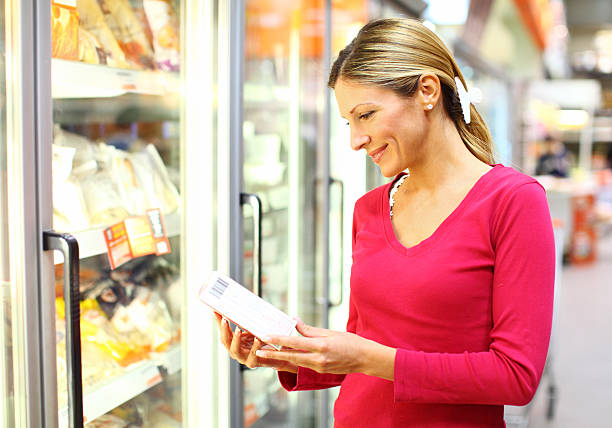 alimentos congelados mujer en la sección de supermercado - supermarket women packaging blond hair fotografías e imágenes de stock