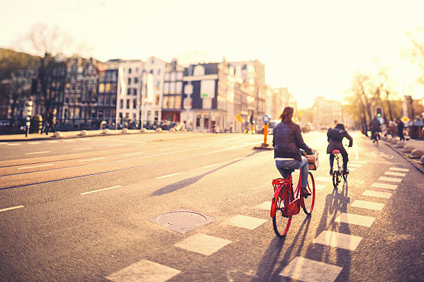personas en las bicicletas en amsterdam calles al atardecer - amsterdam canal netherlands dutch culture fotografías e imágenes de stock