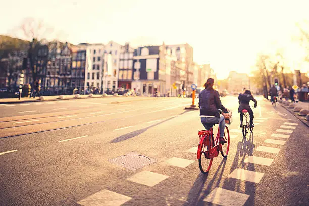 Photo of People on bikes in Amsterdam streets at sunset