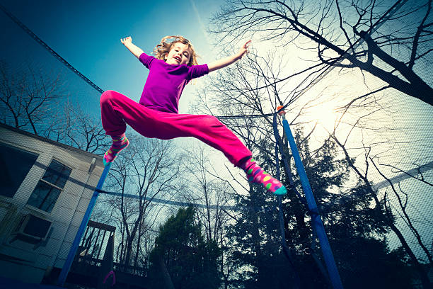 Happy child bouncing joyfully on a trampoline in a sunny backyard, enjoying a fun-filled summer day full of laughter and carefree movement