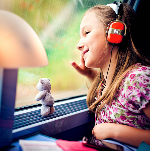 Little girl looking in the train window and listening to music