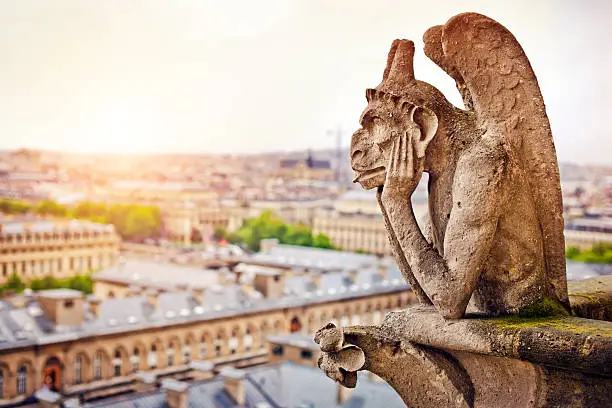 Gargoyle sitting on Notre Dame Cathedral and looking on Paris cityscape